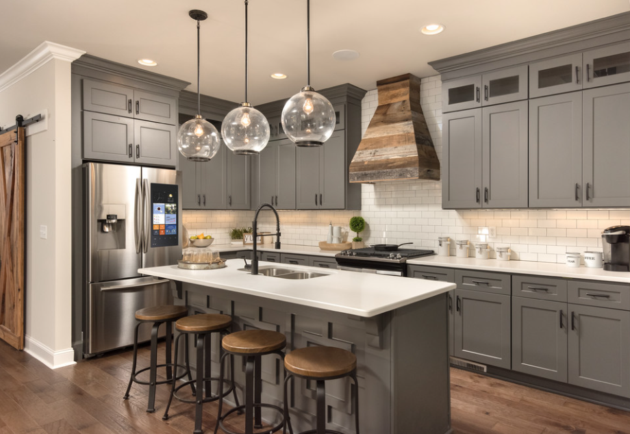 Neutral gray cabinetry is beautifully accented with oil rubbed bronze accents and distressed barn wood
