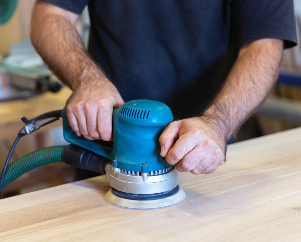Sanding a wood surface with orbital sander in a workshop