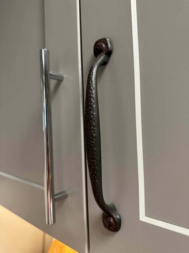 2 different decorative handles on a kitchen cabinet
