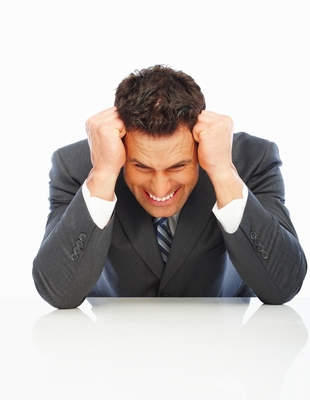 Frustrated Guy with elbows on desk holding head
