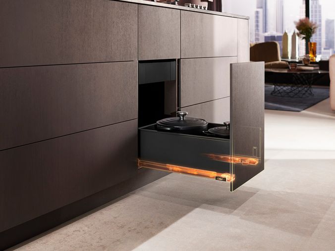 Modern kitchen with a built in pull out ovendrawer open showing pots inside and an orange glow along the bottom edge