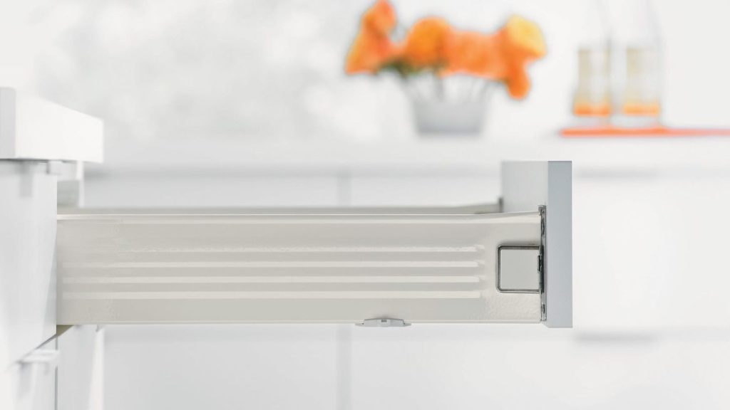 Open white kitchen drawer extended from a cabinet in a bright minimalist kitchen