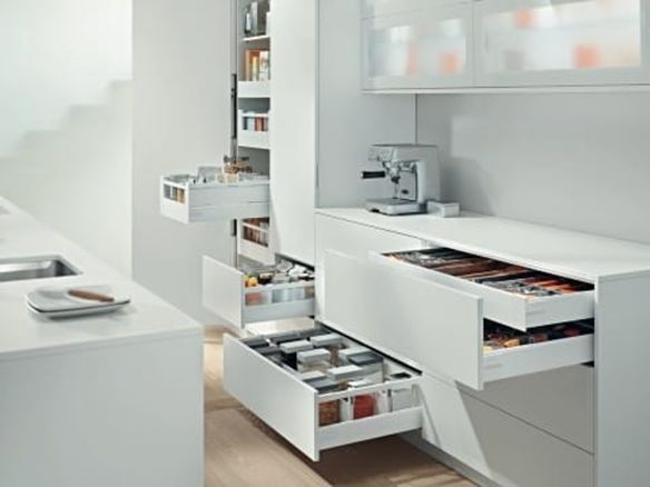 Modern white kitchen with multiple open drawers revealing organized pantry items