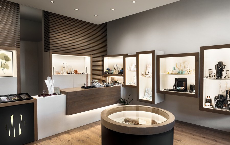 Modern jewelry store interior with wall displays glass cases and a round central display table softly lit