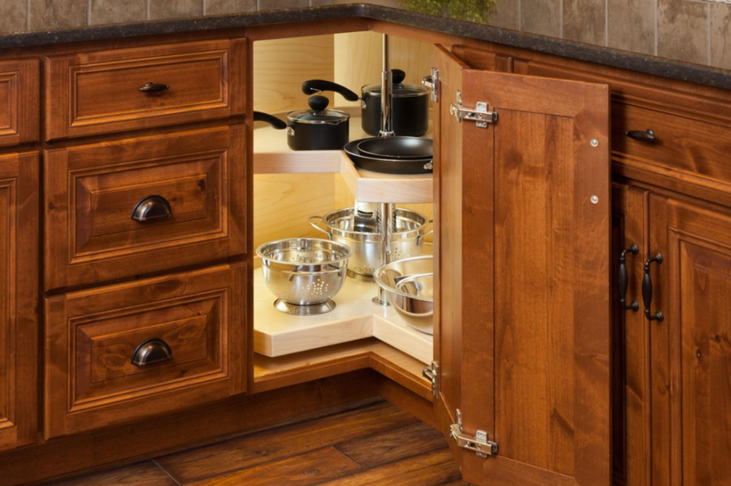 Open base kitchen cabinet with a pull out shelf holding pots pans and colanders visible inside