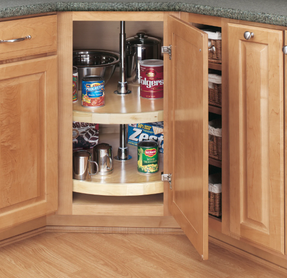 Corner kitchen cabinet with a rotating Lazy Susan shelf showing cans mugs and metal cups inside with the doors open