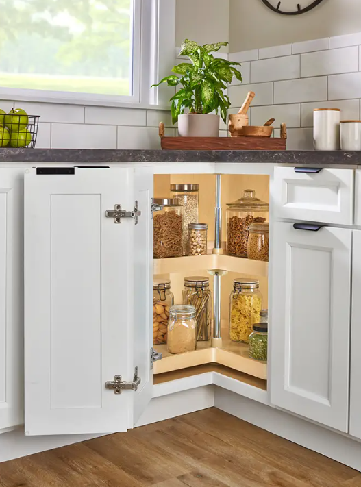 Corner L shaped kitchen cabinet with the door open revealing shelves of jars with pasta nuts and cereals